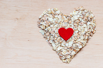 Oat flakes cereal heart shaped on wooden surface.