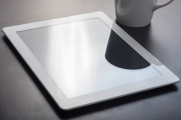 Tablet device on table with coffee mug