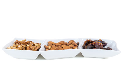 Walnuts almonds and dates in a white dish