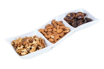 Walnuts almonds and dates in a white dish
