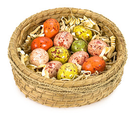 Colorful painted easter eggs in brown basket isolated on white