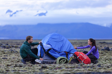 Tent - people pitching tent on Iceland at dusk