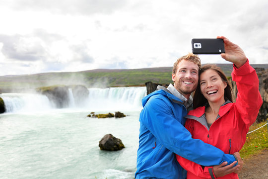 Selfie couple taking smartphone picture waterfall