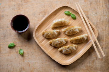 Bamboo tray with japanese pan fried gyoza, rustic wooden surface