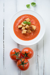 Tomato soup Gazpacho over white wooden background, above view