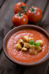 Gazpacho with croutons in a ceramic bowl, dark wooden background