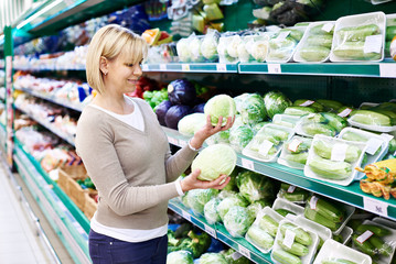 Woman buys white cabbage in store