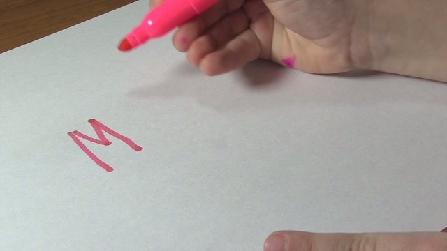 The child learns to write the word MOTHER. Close-up.