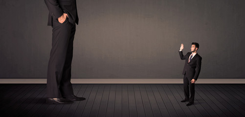 Obraz premium Little bussinesman in front of a giant boss legs concept