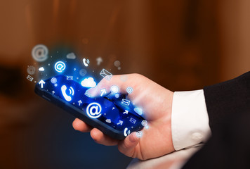 Business man holding smart phone with media icons