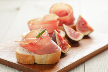 canapes with jamon and figs on wooden board