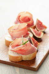 canapes with jamon and figs on wooden board