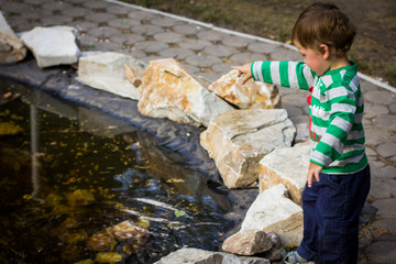 little boy playing by the fountain