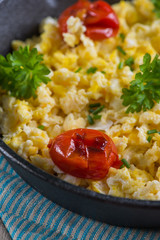 scrambled egg with grilled tomato in vintage iron pan