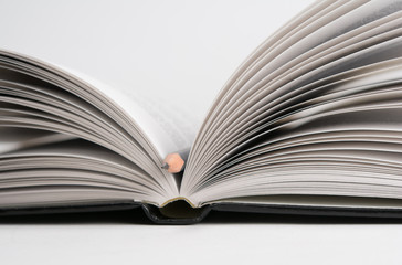 Open book with pencil in the middle. Focus on pencil