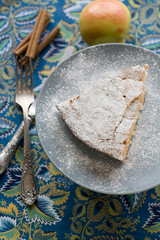 A piece of apple pie plate lying on gray, cinnamon sticks, apple