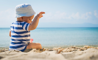 The cute baby boy playing on the beach. Little boy sitting on th