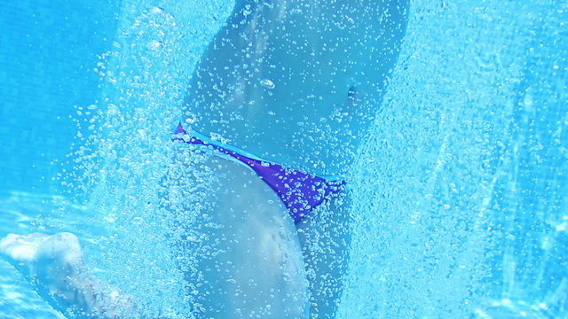 Cute teen girl dives in blue pool jumping in the water