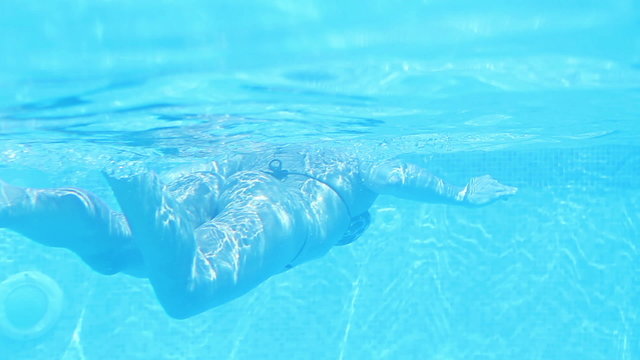 Young pretty woman swimming in the blue pool