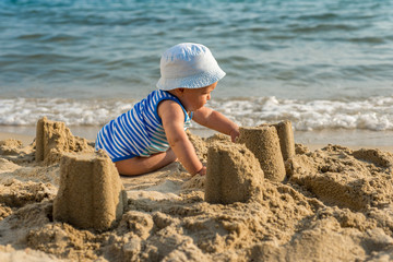 Fototapeta na wymiar The cute baby boy playing on the beach. Little boy sitting on th