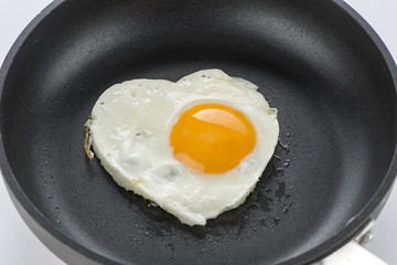 Heart made of fried egg on teflon pan.