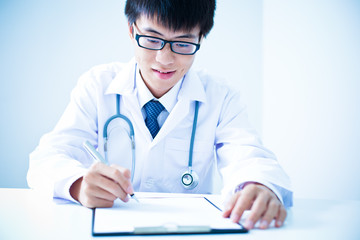 Close-up Of Male Doctor Filling The Medical Form