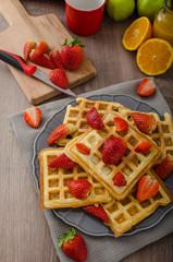 Homemade waffles with maple syrup and strawberries