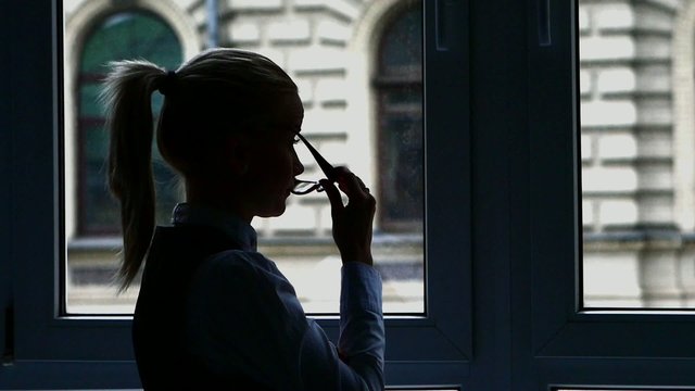 Silhouette Businesswoman standing at the window after a busy day