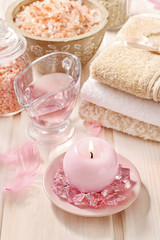 Fototapeta na wymiar Pink spa set: liquid soap, scented candles, towels and rose sea