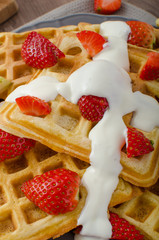 Homemade waffles with maple syrup and strawberries