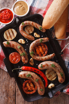 sausages with vegetables on a grill closeup. vertical top view