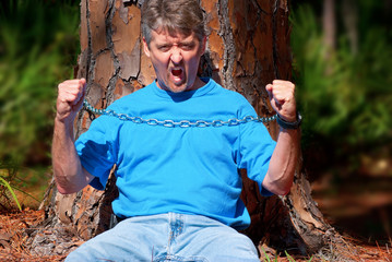 Angry environmentalist protesting deforestation chained to tree