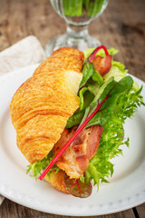 Fresh croissant for breakfast stuffed with bacon, lettuce, chard