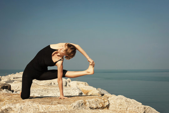 Beautiful woman practicing yoga at seashore