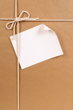 Brown paper package parcel background tied with string or rope and blank message or address label photo vertical
