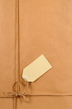 Brown paper package parcel background tied with string or rope and blank message or address label photo vertical