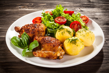 Barbecued chicken legs with boiled potatoes and vegetables