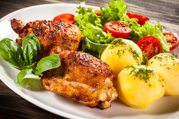 Barbecued chicken legs with boiled potatoes and vegetables