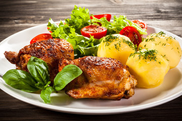 Barbecued chicken legs with boiled potatoes and vegetables