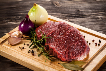 Raw beef on cutting board and vegetables