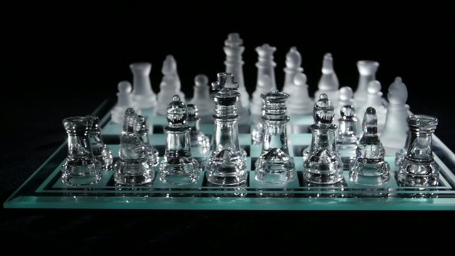 Chess board with chess pieces isolated on black.  Slow motion