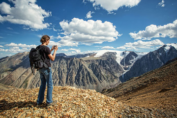 Man in travel in the mountains make photo on mobile phone