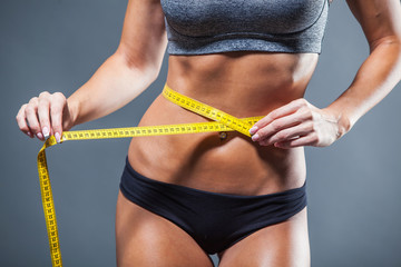 Woman measuring her waist with a yellow tape