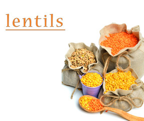 green, red and yellow lentils in the sacks and spoon wooden isol