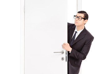 Businessman peeking through an opened door