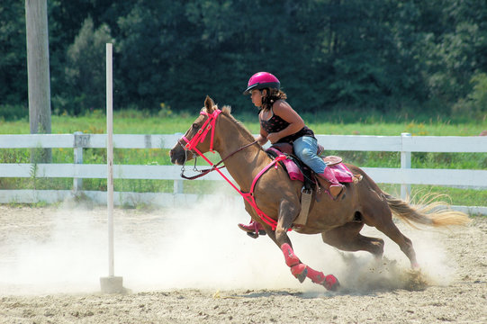Teenage girl on horseback races around a pole