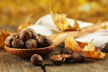 Nutmeg in wooden spoon on table on bright background