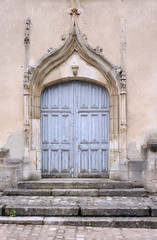 Fototapeta na wymiar Stone portal and a wooden door to the medieval church in France.