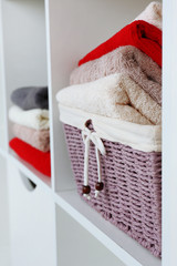 Fototapeta na wymiar Colorful towels with wicker basket on shelf of rack background