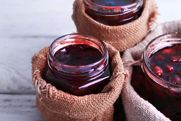 Wandaufkleber Homemade jars of fruits jam in burlap pouches © Africa Studio